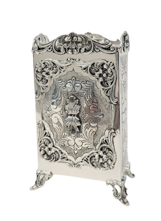 Decorative sterling silver tzedakah box with intricate floral patterns on a white background